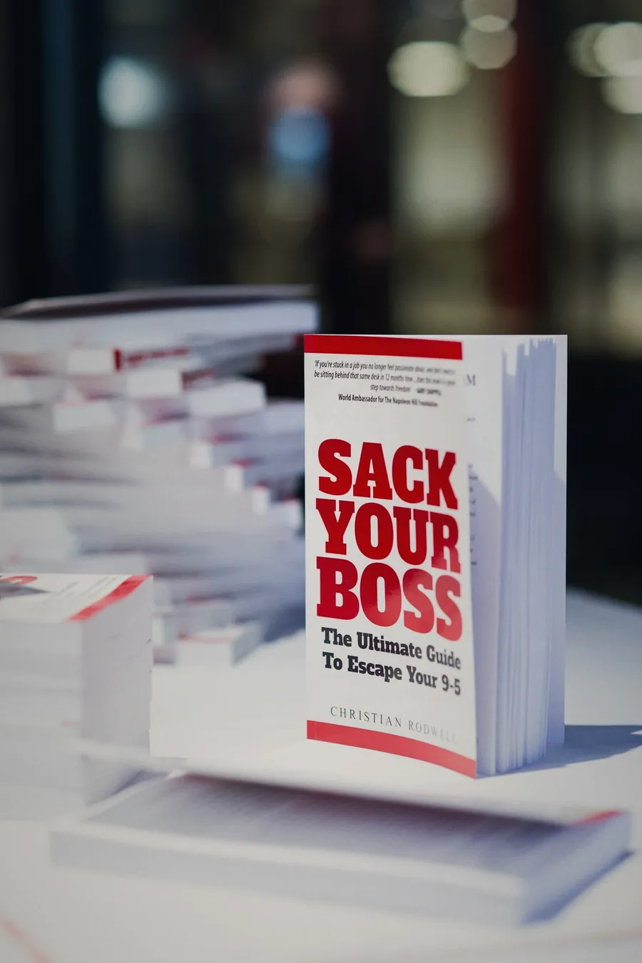 A copy of Sack Your Boss by Christian Rodwell standing on a stack of books